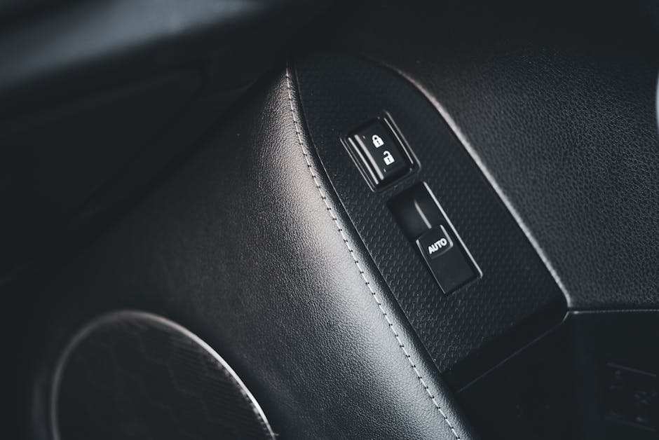 Detailed view of a car interior focusing on lock and auto buttons with leather trim.