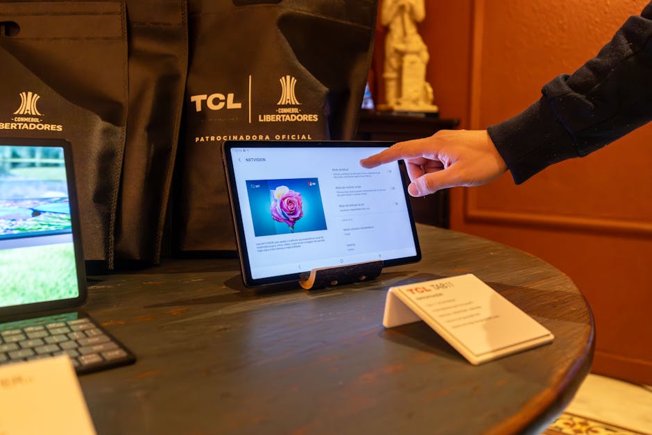 A person using a touchscreen tablet at a technology exhibition showcasing TCL products.